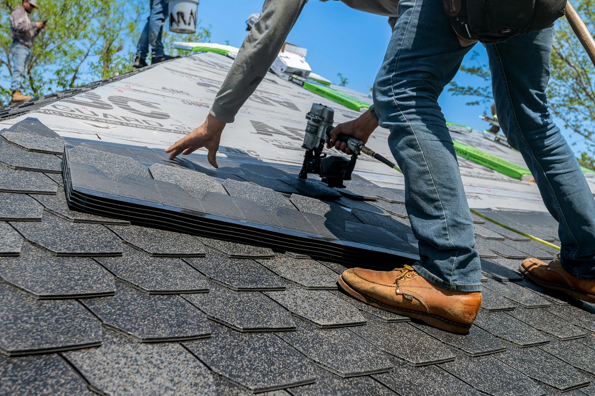 man installing asphalt shingles on a roof
